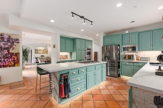 kitchen with light tile patterned floors, green cabinets, a center island, and stainless steel appliances