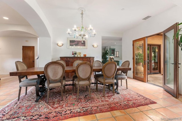 dining space with french doors, light tile patterned flooring, and a chandelier