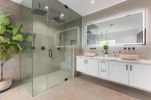 bathroom featuring decorative backsplash, a shower with shower door, vanity, and tile walls