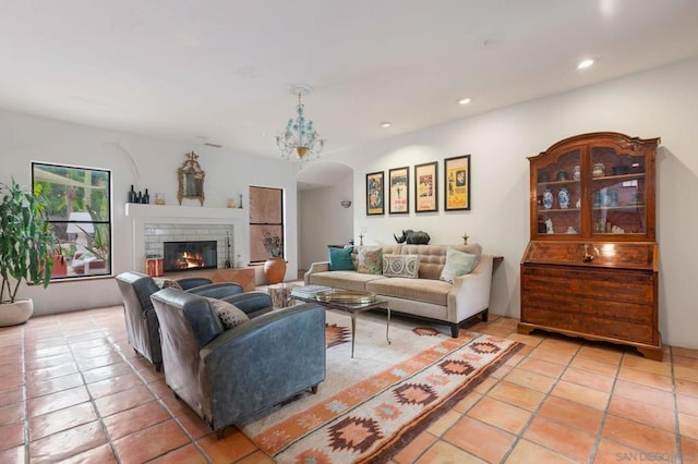 living room with light tile patterned floors, a fireplace, and a notable chandelier