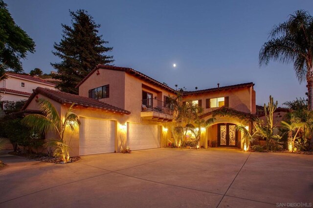 mediterranean / spanish-style home featuring a garage and a balcony