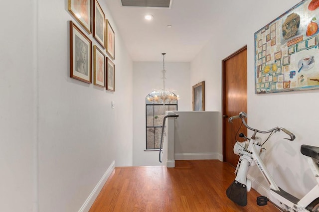 hallway featuring wood-type flooring and a notable chandelier