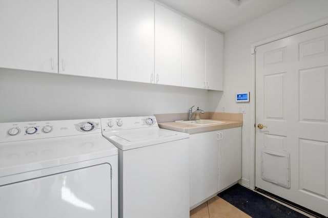 clothes washing area featuring washer and dryer, sink, light tile patterned flooring, and cabinets