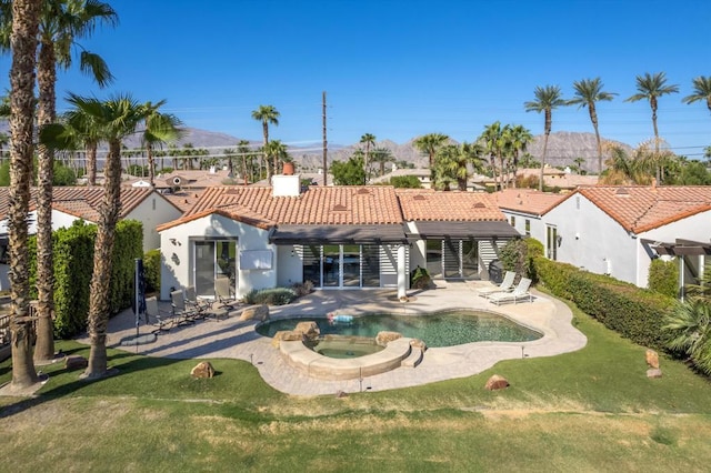 back of property with a lawn, a swimming pool with hot tub, a pergola, and a patio