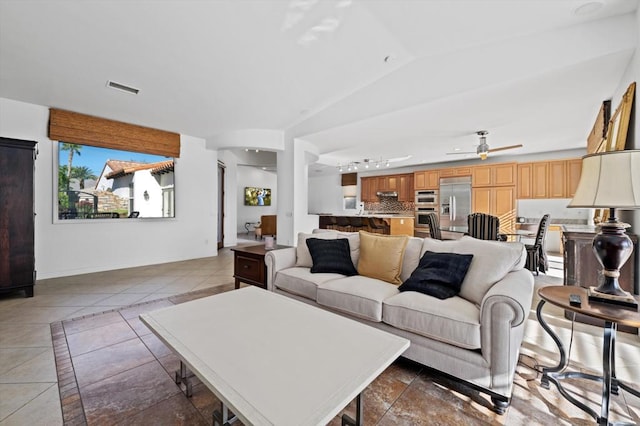 living room featuring dark tile patterned floors, vaulted ceiling, and ceiling fan