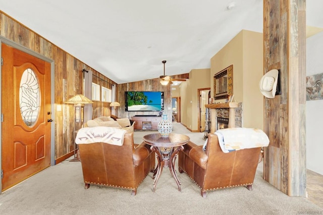 carpeted living room with wooden walls, ceiling fan, a fireplace, and vaulted ceiling