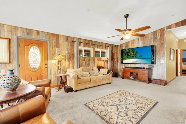 living room with ceiling fan, carpet floors, wooden walls, and vaulted ceiling