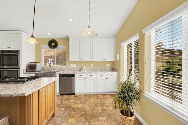 kitchen featuring stainless steel appliances, a healthy amount of sunlight, decorative light fixtures, and white cabinetry