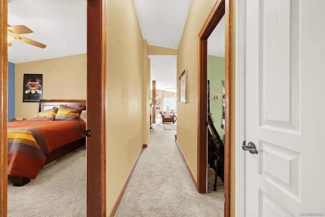 hall with light colored carpet and vaulted ceiling