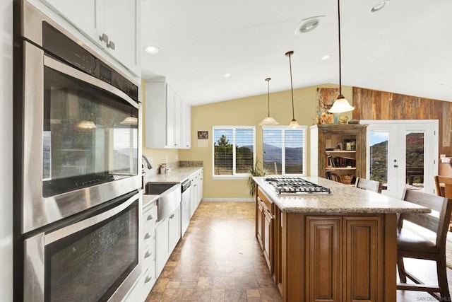 kitchen featuring pendant lighting, white cabinetry, appliances with stainless steel finishes, a center island, and a breakfast bar area