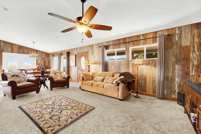 carpeted living room featuring ceiling fan with notable chandelier, lofted ceiling, and wood walls