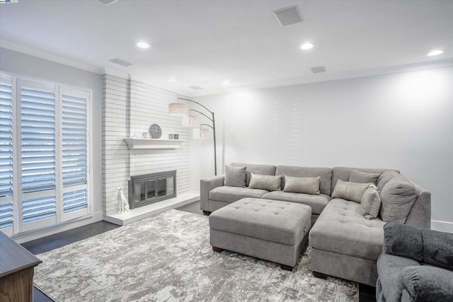 living room with crown molding, a fireplace, a healthy amount of sunlight, and hardwood / wood-style flooring