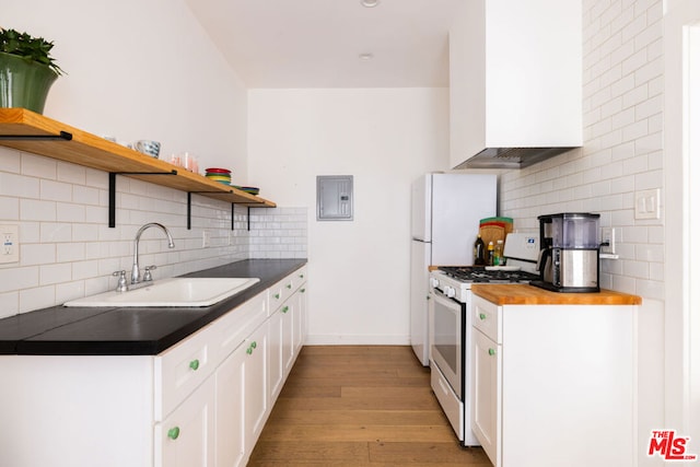 kitchen featuring white gas range, white cabinetry, sink, light hardwood / wood-style flooring, and decorative backsplash