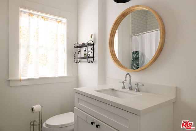 bathroom with a wealth of natural light, vanity, and toilet