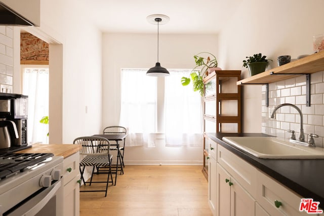 kitchen with pendant lighting, a healthy amount of sunlight, white cabinetry, and sink