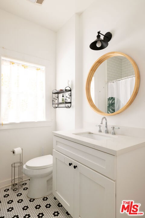 bathroom with toilet, vanity, and tile patterned floors