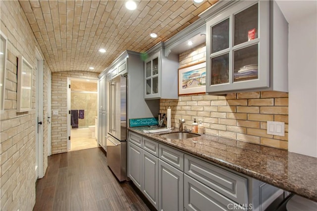 kitchen featuring dark stone counters, gray cabinets, ornamental molding, and sink