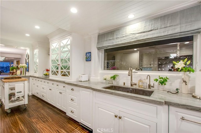 bar with white cabinetry, sink, and light stone countertops