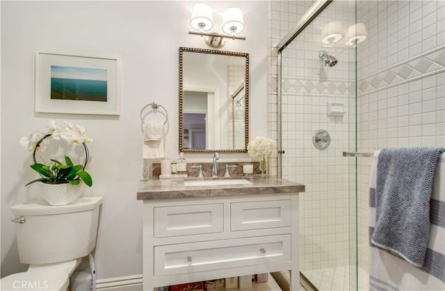 bathroom featuring a shower with door, vanity, and toilet