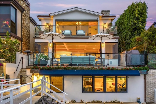 back house at dusk featuring a balcony