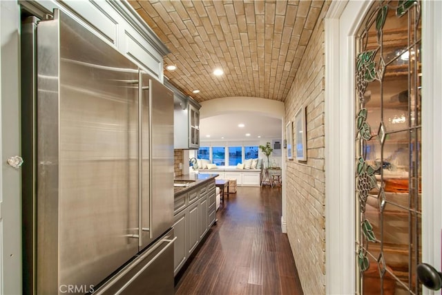 hallway with dark hardwood / wood-style floors, brick ceiling, and vaulted ceiling