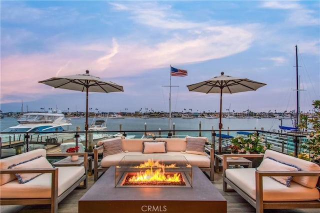 patio terrace at dusk with a water view and an outdoor living space with a fire pit