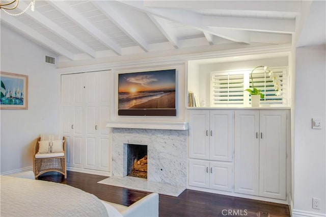 living room featuring lofted ceiling with beams, dark wood-type flooring, and a premium fireplace