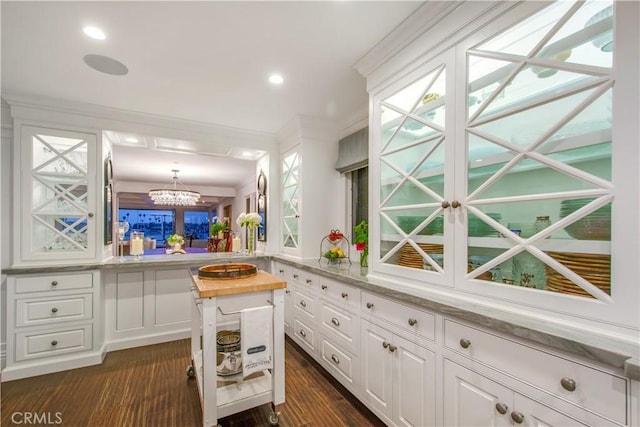 kitchen with butcher block counters, hanging light fixtures, ornamental molding, white cabinetry, and kitchen peninsula