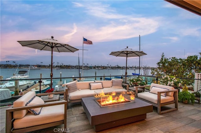 patio terrace at dusk with a water view and an outdoor living space with a fire pit