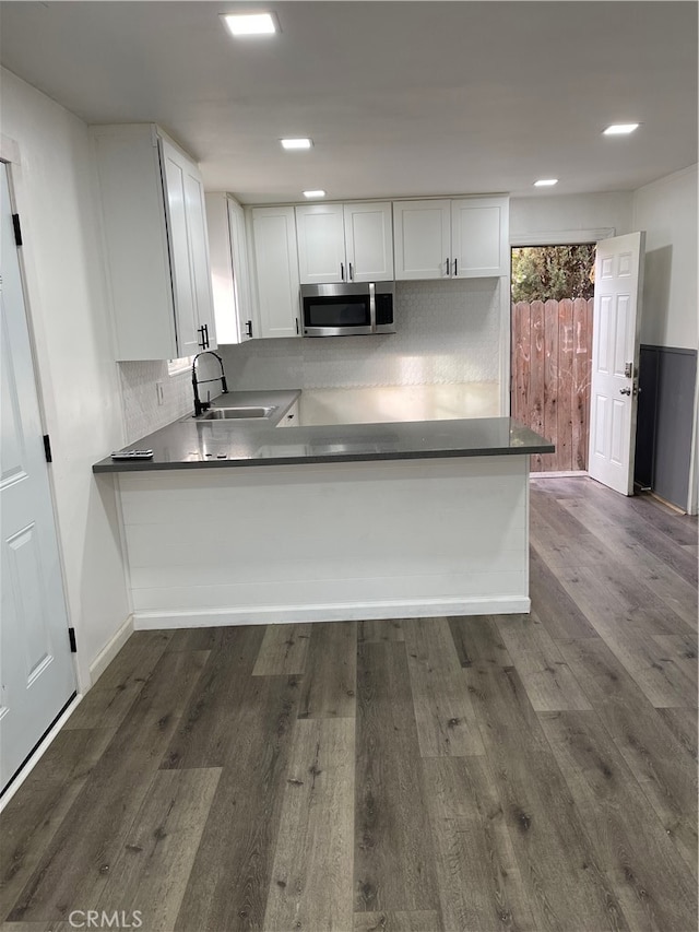 kitchen featuring dark wood-type flooring, sink, kitchen peninsula, and white cabinets