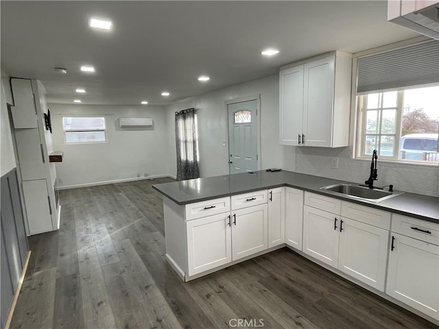 kitchen featuring sink, dark hardwood / wood-style flooring, kitchen peninsula, white cabinets, and a wall mounted AC