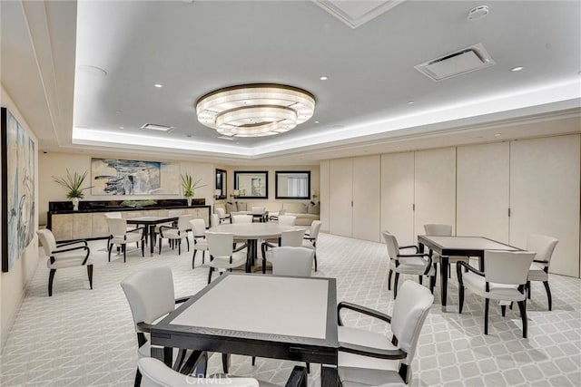 dining space with a tray ceiling, light colored carpet, and visible vents