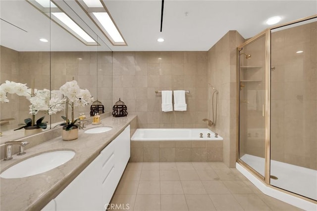 full bath featuring a skylight, a shower stall, tile walls, and a sink