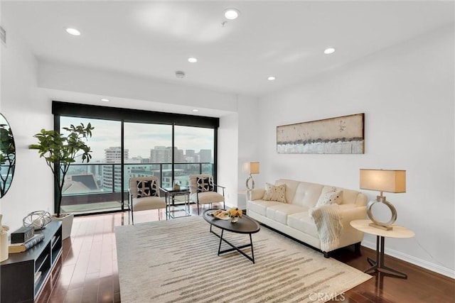 living area featuring dark wood-style floors, a city view, recessed lighting, and baseboards