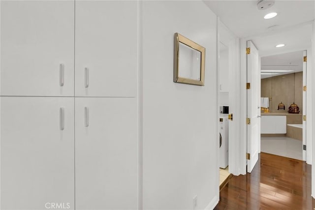 hall featuring washer / dryer, dark wood finished floors, and recessed lighting