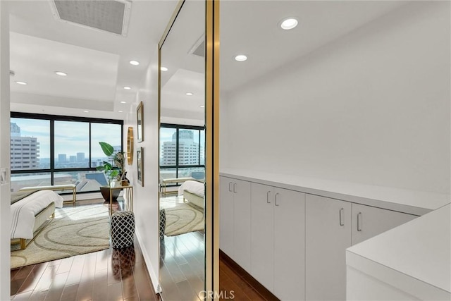 interior space with recessed lighting, a city view, wood finished floors, visible vents, and floor to ceiling windows