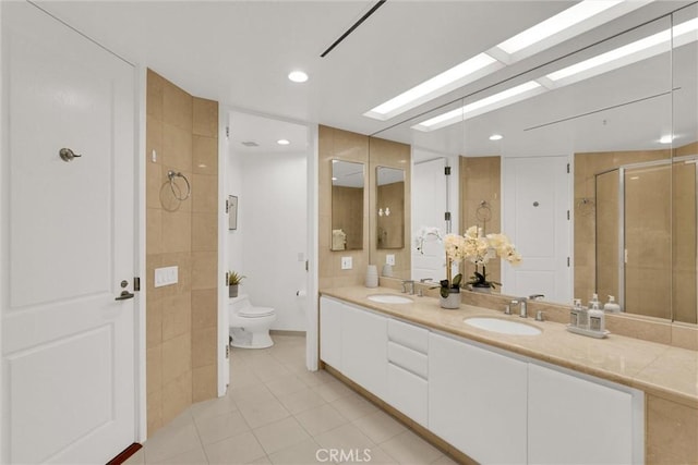 full bathroom featuring a skylight, a sink, a shower stall, and toilet