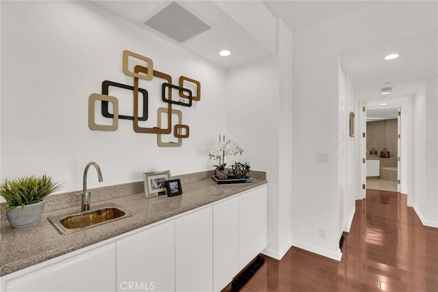 bar featuring dark wood-style floors, baseboards, a sink, and recessed lighting