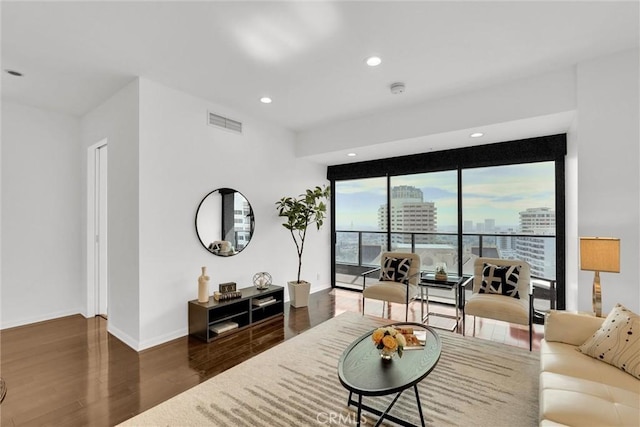 living area with baseboards, visible vents, wood finished floors, a view of city, and recessed lighting