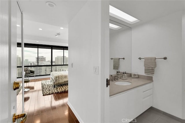 bathroom with a skylight, baseboards, wood finished floors, a city view, and vanity