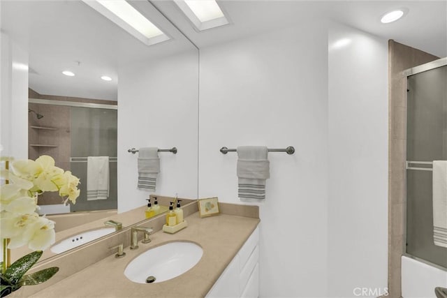 bathroom featuring a skylight, recessed lighting, a shower with door, and vanity