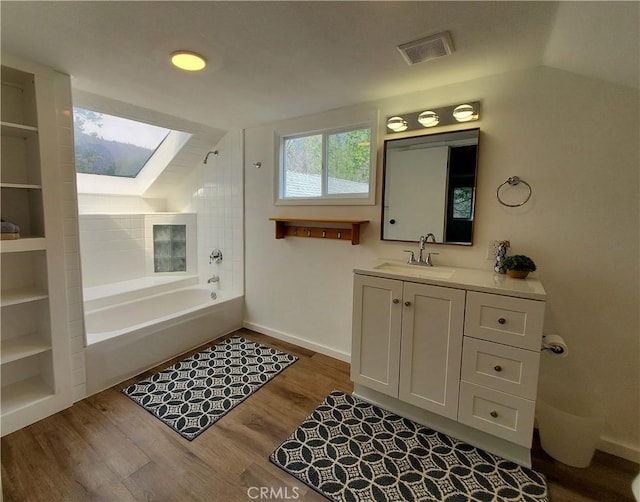 bathroom featuring shower / bath combination, vaulted ceiling with skylight, vanity, and wood-type flooring