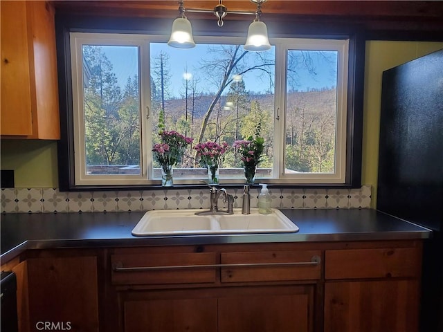 kitchen featuring decorative backsplash, sink, a healthy amount of sunlight, and decorative light fixtures