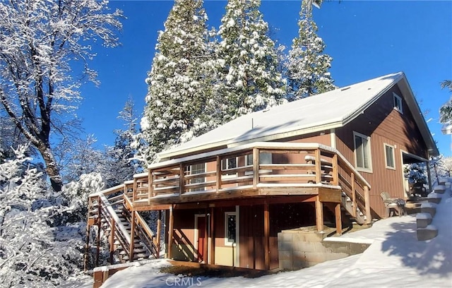 snow covered rear of property featuring a wooden deck