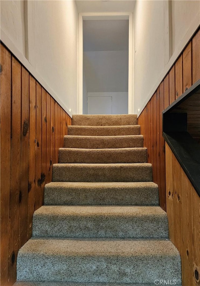 stairway featuring wood walls