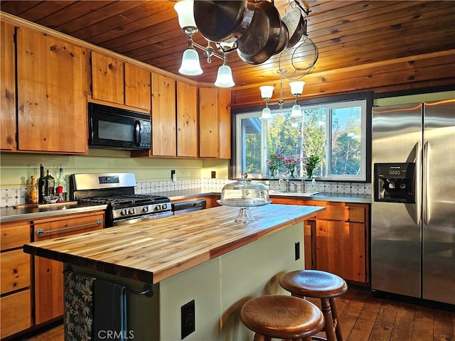 kitchen featuring wood counters, appliances with stainless steel finishes, a center island, dark hardwood / wood-style floors, and hanging light fixtures