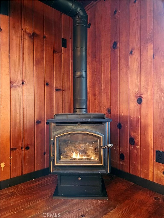 interior details featuring a wood stove, wooden walls, and hardwood / wood-style flooring