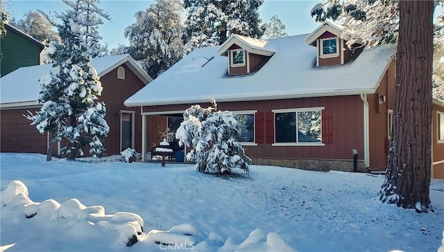 snow covered rear of property featuring a garage