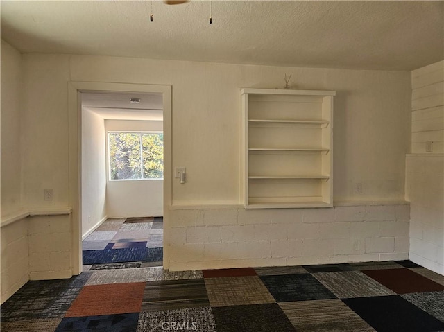 spare room featuring dark carpet and a textured ceiling