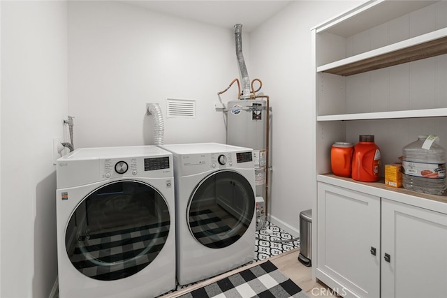 laundry area with water heater, separate washer and dryer, and cabinets